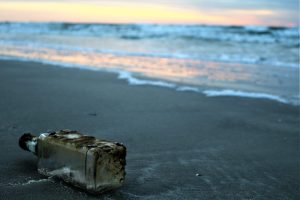 glass bottle at the seashore near sea water photo during golden hour
