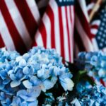 a bunch of blue flowers in front of american flags